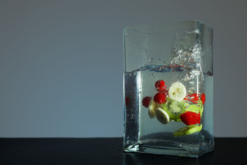 fruit slices dropped into square shaped glass with water