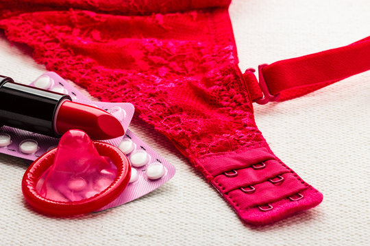 Pills, lipstick and condom with lace lingerie.