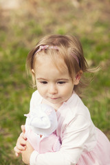 Cute little girl holding a doll outdoors