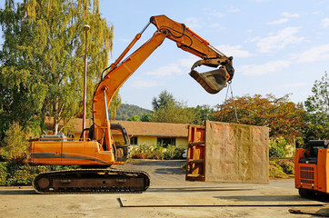 A track hoe excavator places a trench box 