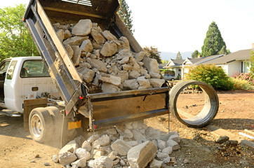 A small dump truck dumps concrete pieces 