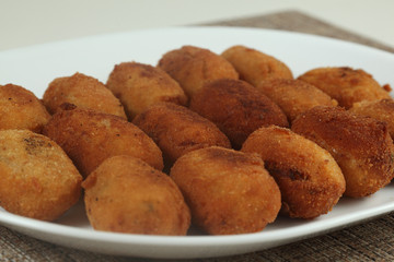 Croquetas e jamón servidas en un plato blanco