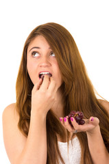 Beautiful young supersticious woman eating grapes