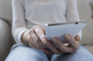 Women who are using a mobile phone sitting on the sofa