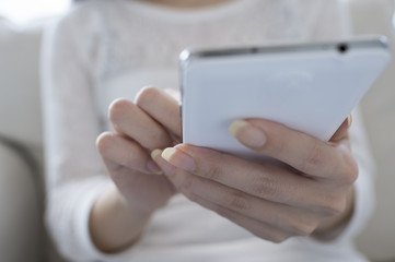 Women who are using a mobile phone sitting on the sofa