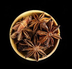 Star anise in wooden bowl, isolated on white