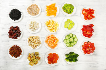 Different products on saucers on wooden table, top view
