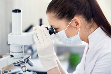 Female scientist looking through a microscope in laboratory