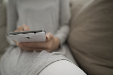 Women are using a mobile phone sitting on the sofa