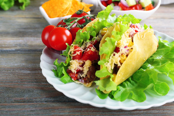 Tasty taco with vegetables on plate on table close up