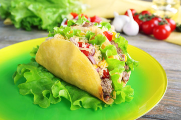 Tasty taco on plate with vegetables on table close up