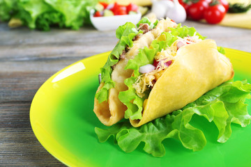 Tasty taco on plate with vegetables on table close up