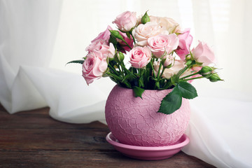 Beautiful roses in pot on fabric background