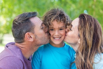 Obraz premium Happy family kissing at camera in the park