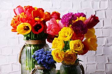 Beautiful flowers in vases on wall background