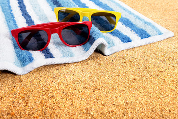 Sunglasses on a summer beach sand background border with couple sunbathing towel photo