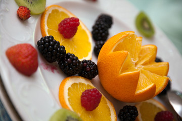 Arancia tagliata a fiore e frutti rossi in primo piano