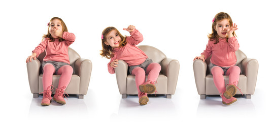 Little girl sitting on armchair with thumb up