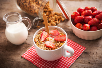 Healthy breakfast. Bowl of milk with granola and strawberries.