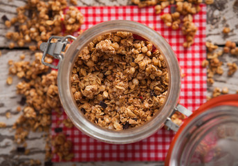 Granola in open glass jar on rustic wooden background