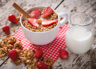 Healthy breakfast. Bowl of milk with granola and strawberries.