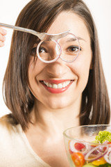 Woman looking through sliced onion having bowl of salad in hand