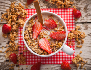 Healthy breakfast. Bowl of milk with granola and strawberries.