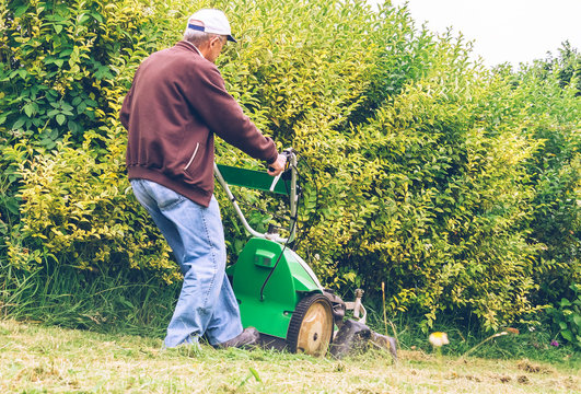 Senior Man Mowing The Lawn With Lawnmower 