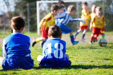 Obraz premium young boys in uniform watching their team while playing football