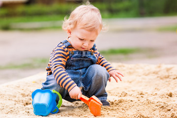 Cute baby boy playing with sand