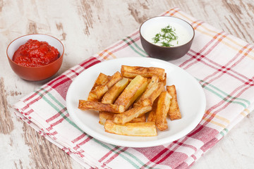 fried french fries with tomato sauce and herbs, close-up