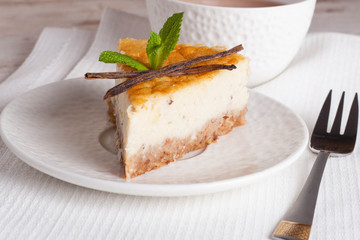 Vanilla cheesecake on a white plate and cup of tea, close up