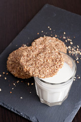glass of milk and oat cookies on a dark background