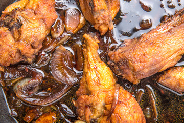 Deep fried chicken in with black soy gravy in a saute pan