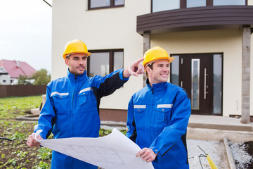 smiling builders with blueprint pointing finger