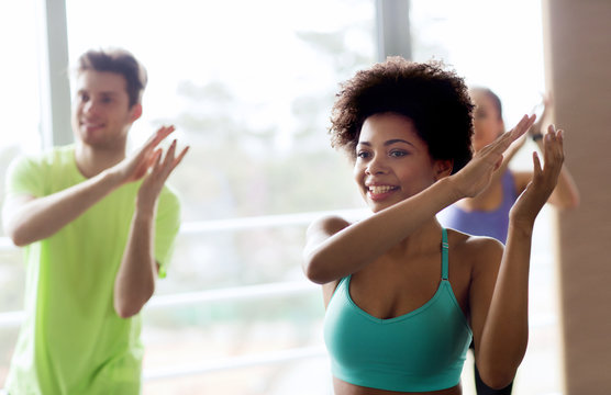 group of smiling people dancing in gym or studio