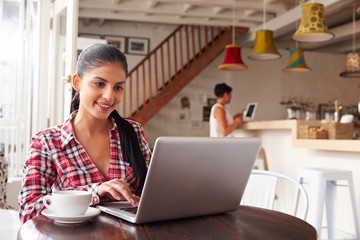 Young woman using laptop in a cafe