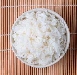 bowl of white steamed rice  on bamboo mat.