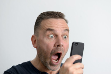 Überraschter attraktiver Mann mit Handy