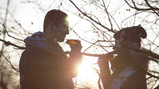 Close up of young beautiful couple clinking glasses, drinking special warming drinks and having a talk in romantic sunset surroundings