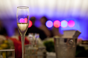 Glass with champagne lit by nightclub lights