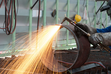 worker in factory cutting steel pipe using metal torch