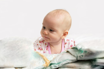 Adorable baby girl looking over a pile of diapers