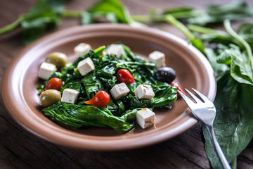 Spinach with cheese, olives and pepper drops