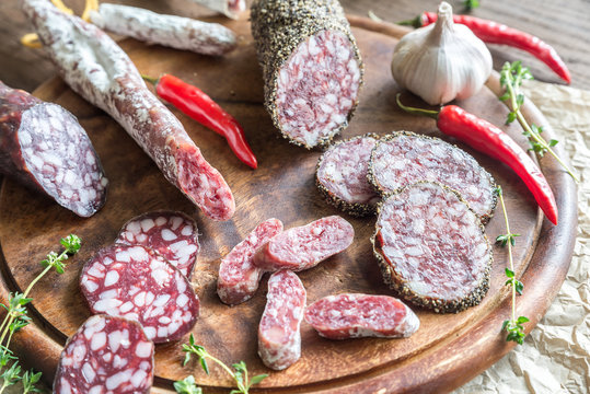 Slices of saucisson, fuet and salami on the wooden board