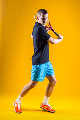 Tennis player on yellow background. Studio shot
