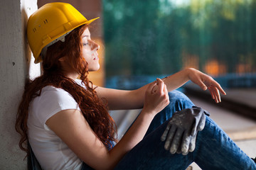 Woman Bricklayer with Overalls and Helmet Smoking a Cigarette