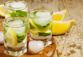 Glass of water with fresh lemon, ice and mint, selective focus