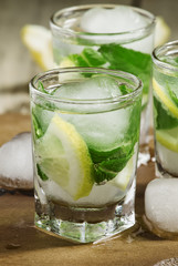 Glass of water with fresh lemon, ice and mint, selective focus