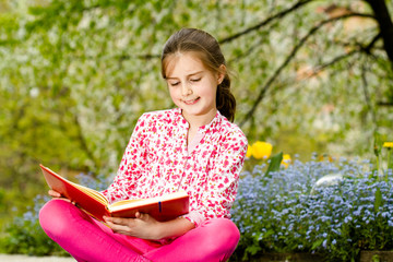 Fototapeta premium Young girl reading a book outdoor